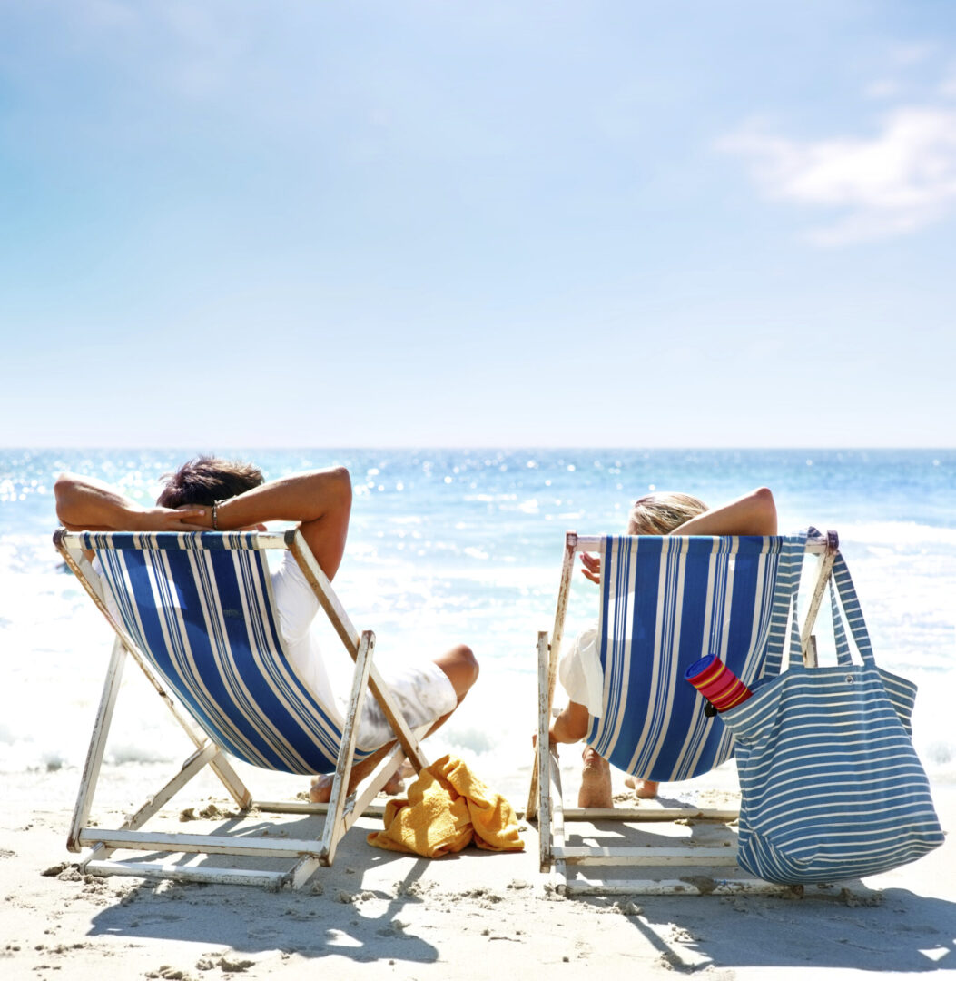 Rear view of a couple on a deck chair relaxing on the beach